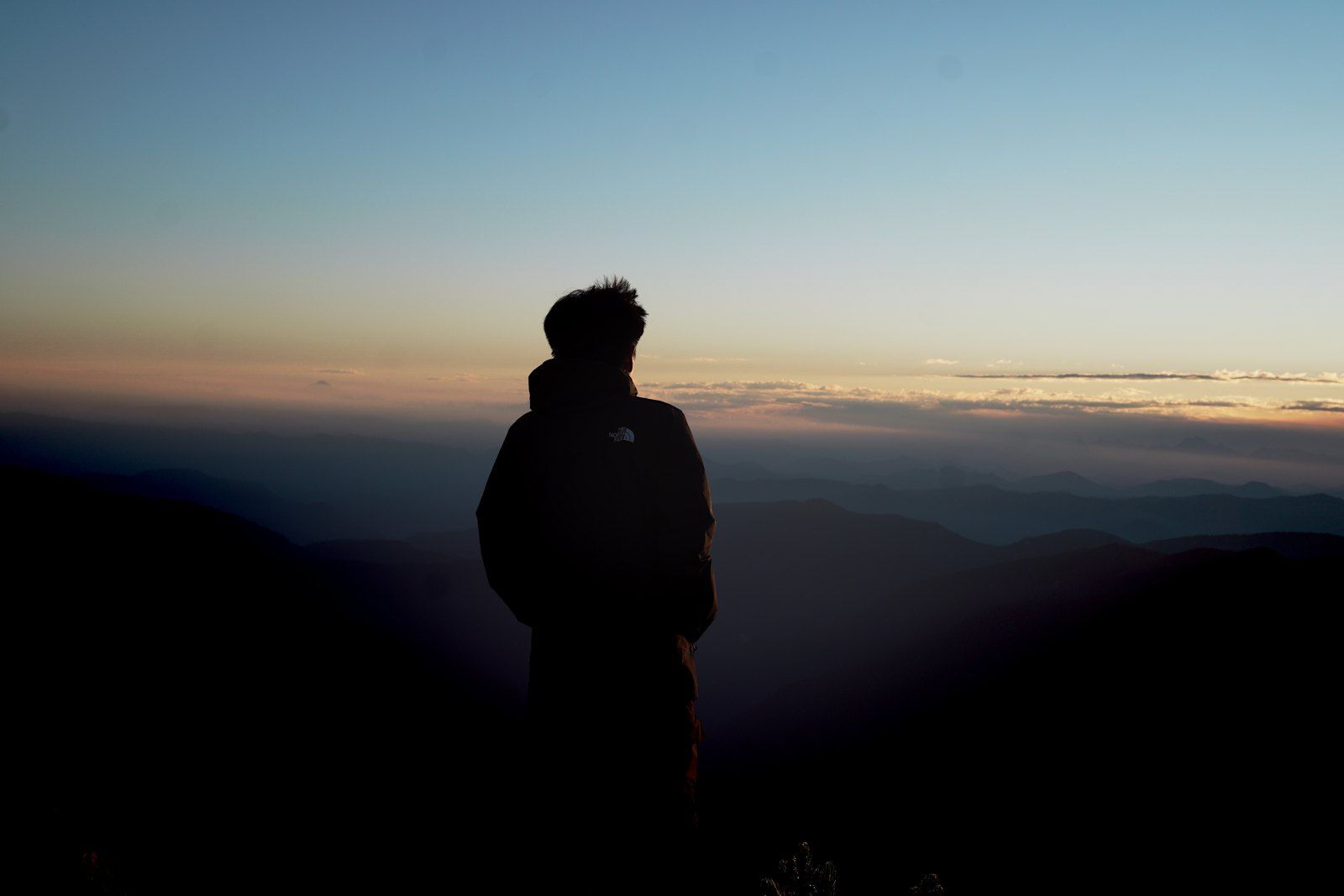 A person looking over mountain ridges at sunset